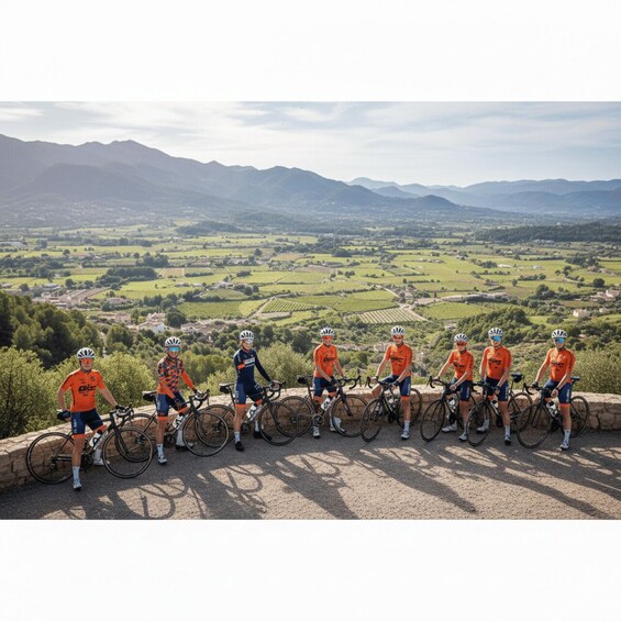 A group of cyclists in orange jerseys on a gravel path with a scenic view of rolling hills and vineyards. 2