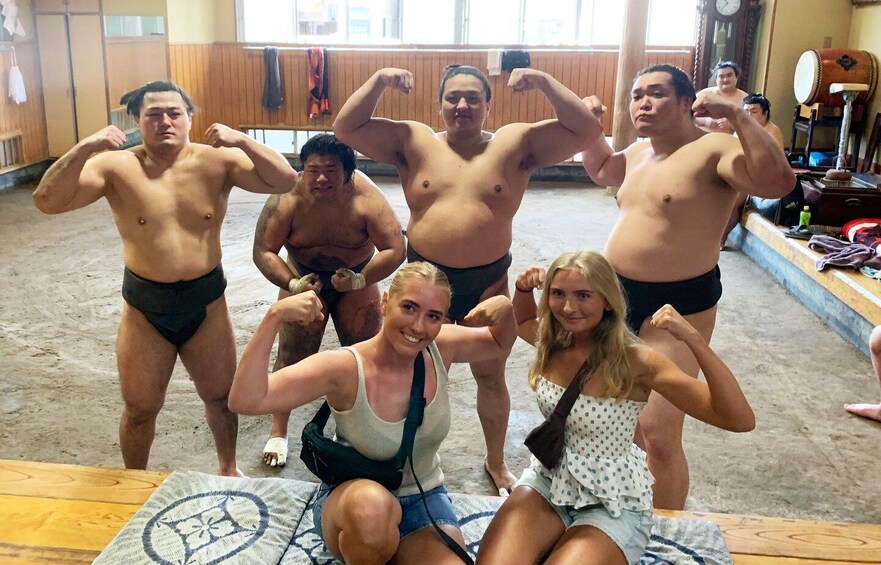 A group of people flexing their muscles in a room with wooden walls and a large clock. 2