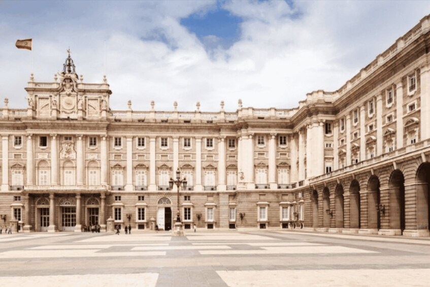 A large, historic building with classical architecture, a central courtyard, and a flag flying. 5