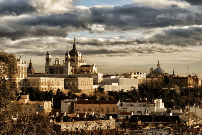 A cityscape with prominent historical architecture, including a large cathedral with multiple domes and spires, surrounded by modern buildings and a cloudy sky. 2