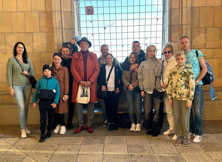 A group of people standing in front of a building with a barred window. 4