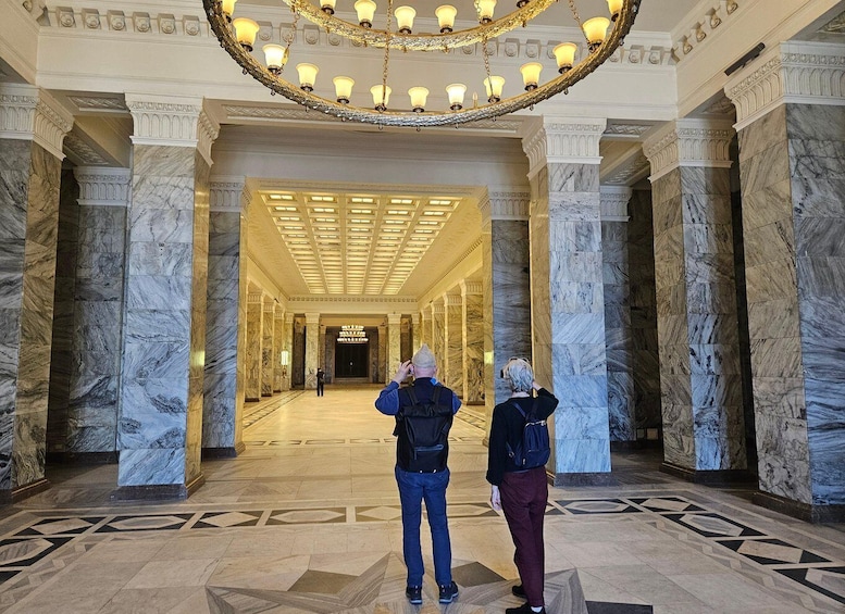 A grand hallway with marble columns and a large, ornate chandelier. 1