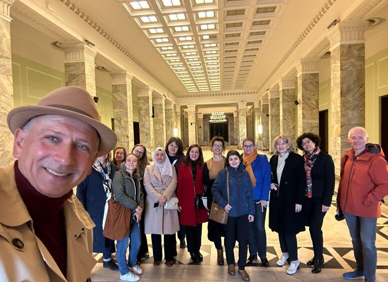 A group of people in a grand hallway with marble columns and a high ceiling. 5
