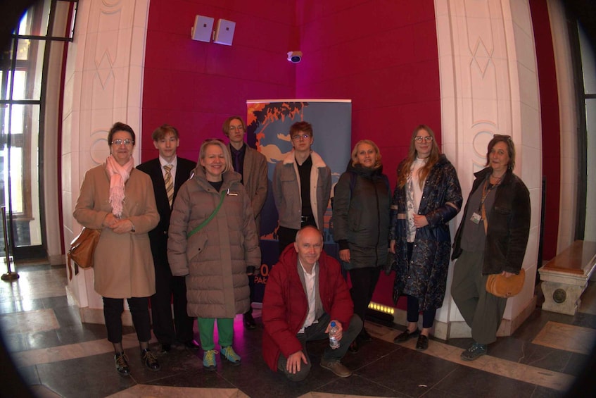 A group of people in a hallway with red walls and a poster in the background. 2
