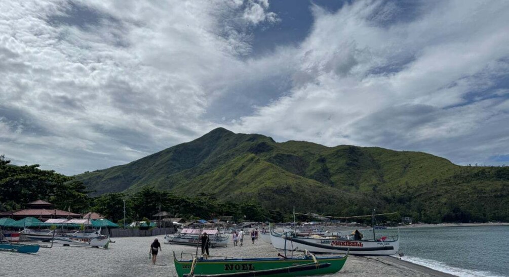 A beach with boats, a mountain, and a cloudy sky. 5
