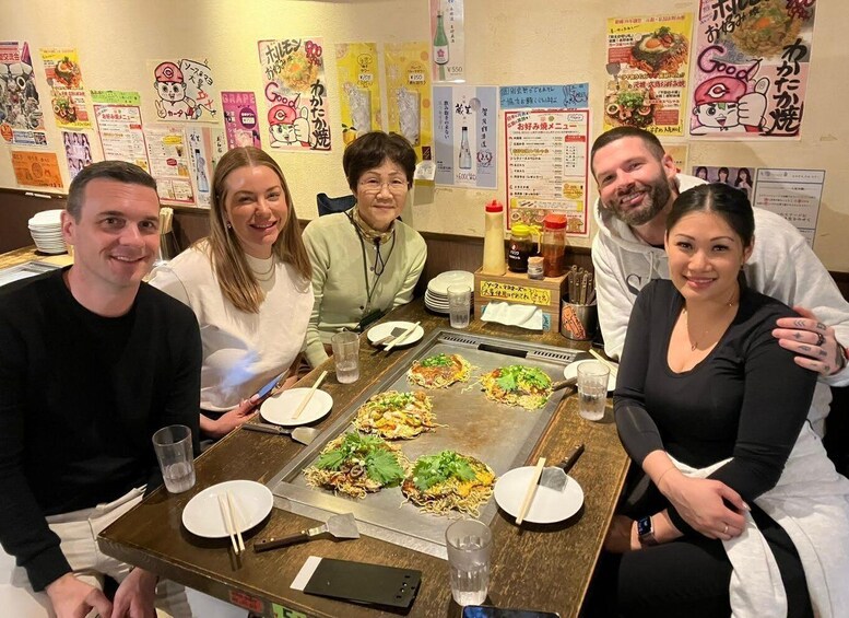 A group of people dining at a restaurant with a variety of food items on a grill. 5