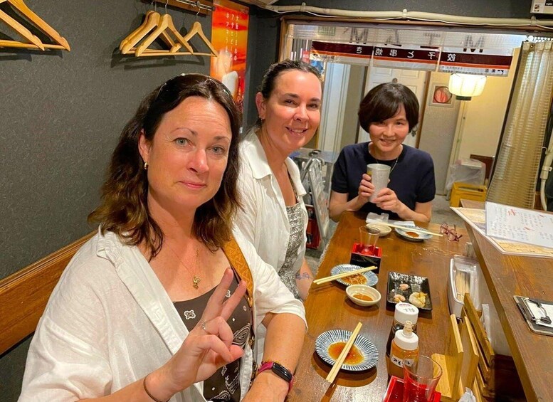 Three people sitting at a wooden table with food and drink items. 2