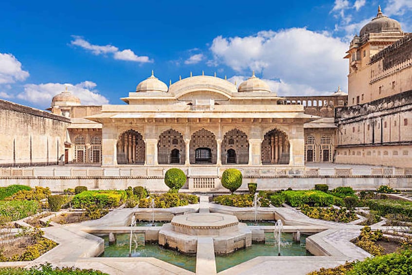 A historic building with domes and arches, surrounded by a formal garden and a central water feature. 2