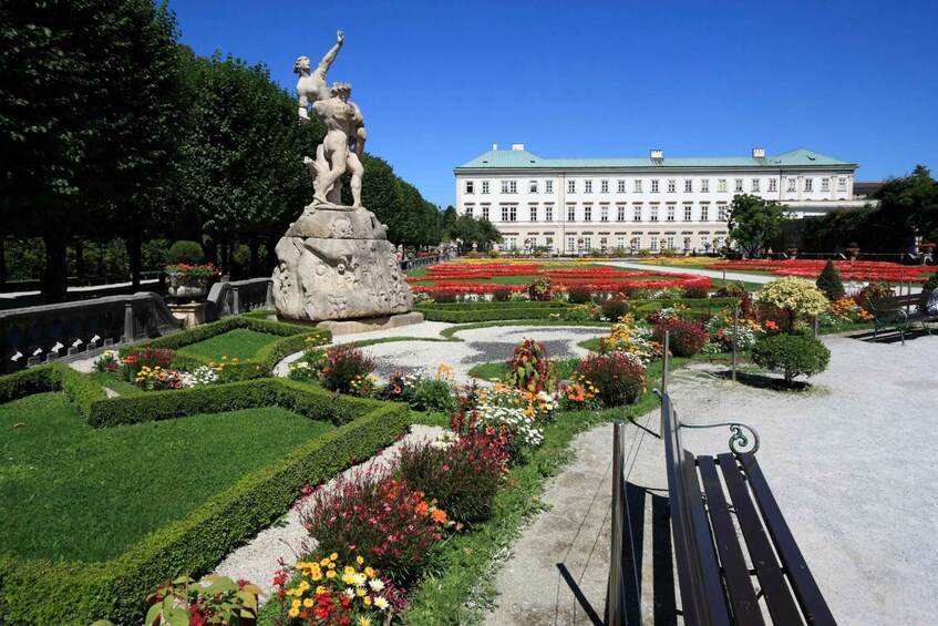 A statue in a garden with a large building in the background. 1