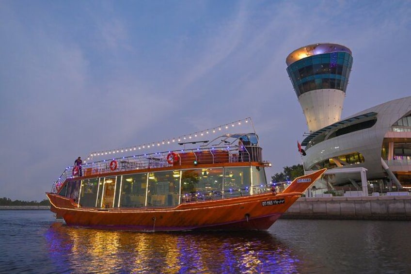 A boat with a cabin and deck, docked near a modern building with a tower. 2