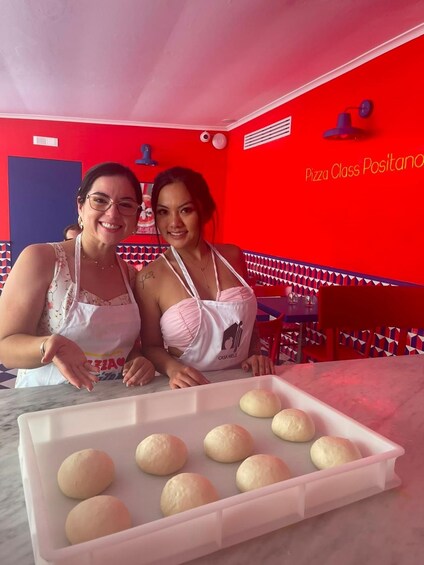 Two people in a red-themed room with a tray of doughnuts. 2