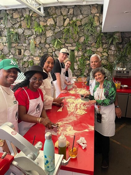 A group of people preparing food at a counter with a stone wall background. 5
