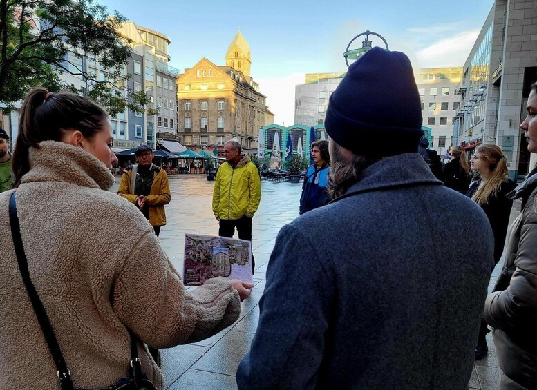 A group of people in an urban square with historical buildings, including a church with a dome. 2