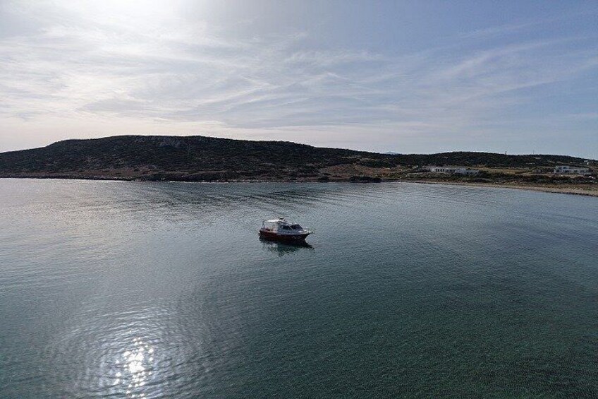 A calm body of water with a small boat in the center, surrounded by a hilly landscape and a clear sky. 3