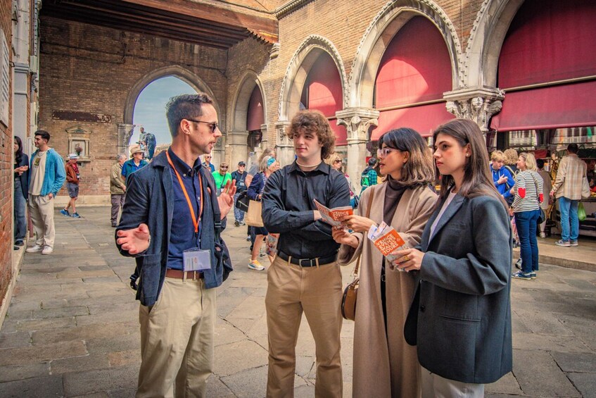 A group of people standing in an outdoor area with arches and brick walls. 1