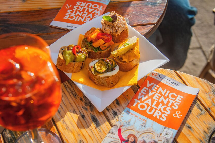 A table with food items and a brochure titled "Venice Events Walks & Tours". 4