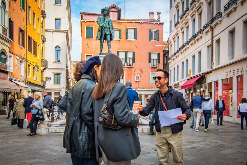 A busy urban square with people walking and a statue in the center. 3