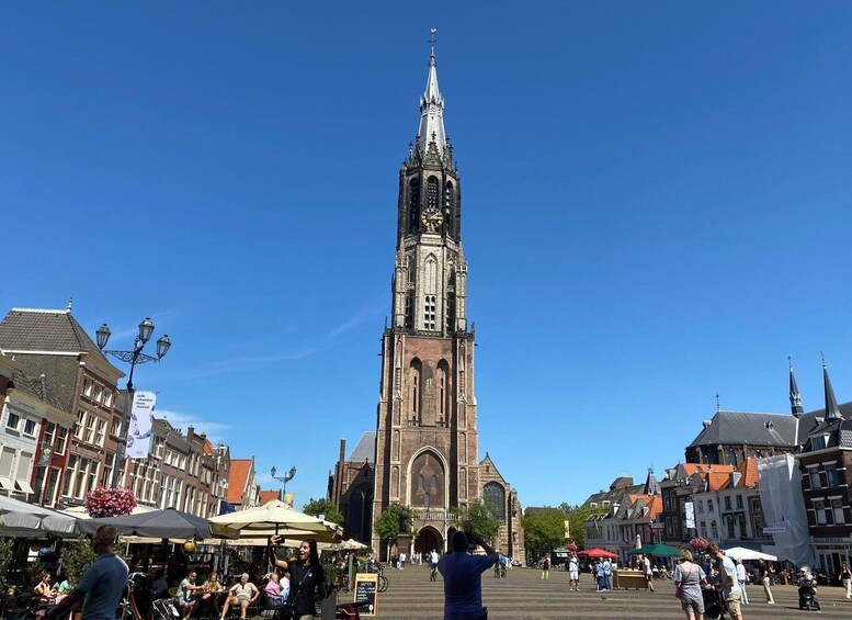 A historic church with a tall spire, surrounded by a bustling square with people and outdoor cafes. 3