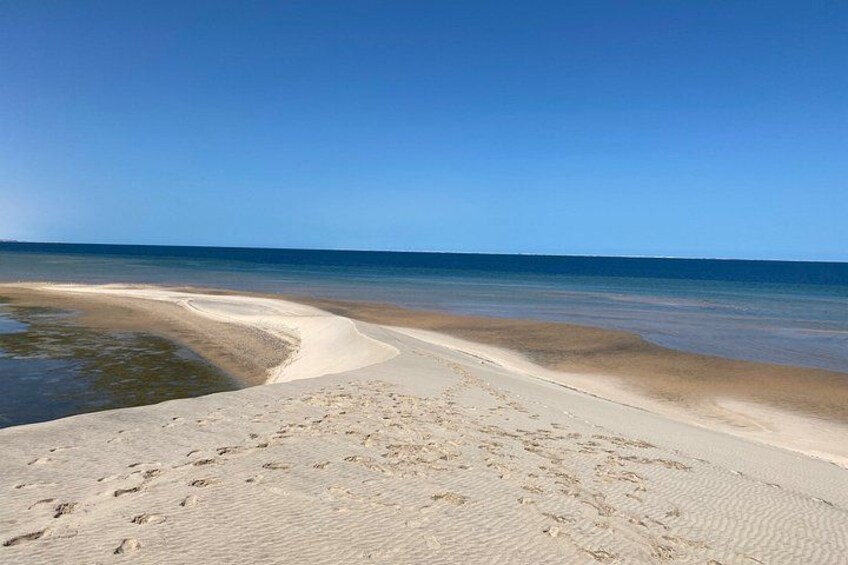 A beach with a curved shoreline, clear blue sky, and calm sea. 3