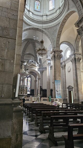 An interior of a church with high ceilings, arched windows, and a large chandelier. 2