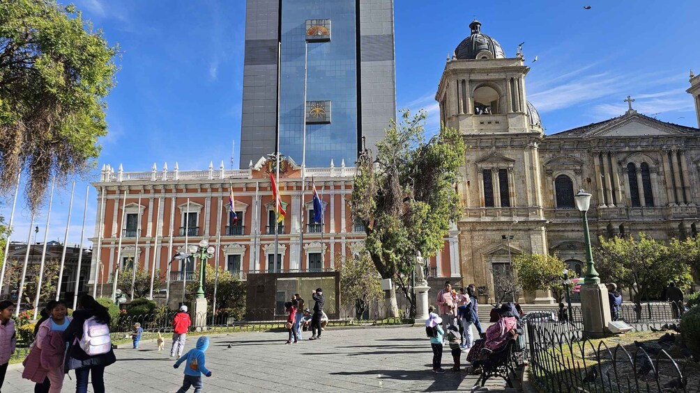 A plaza with people walking, a historic building, and a modern skyscraper. 4