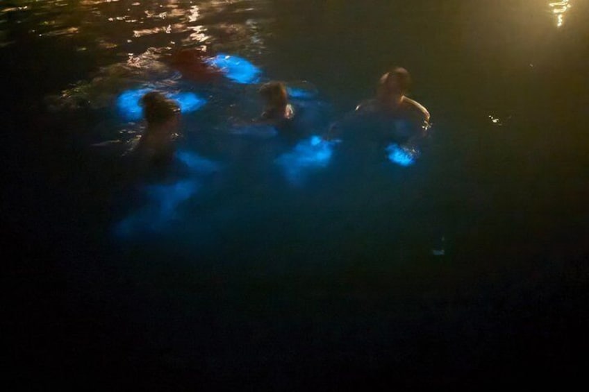 Personer som simmar i en mörk pool med blått ljus. 5