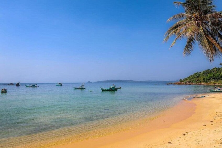 A beach with clear turquoise water, a sandy shore, and several small boats. 3