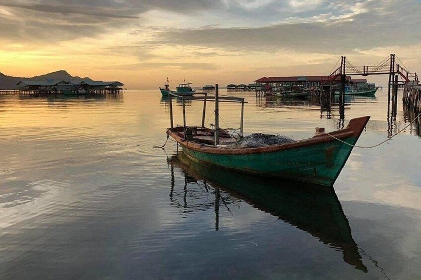 A calm lake with boats, a wooden dock, and distant buildings. 4