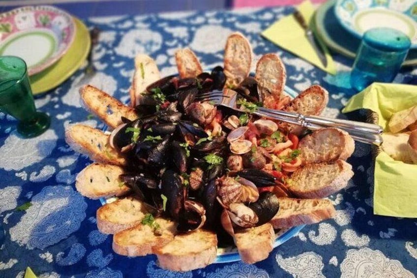 A seafood dish with mussels and bread on a patterned tablecloth. 1