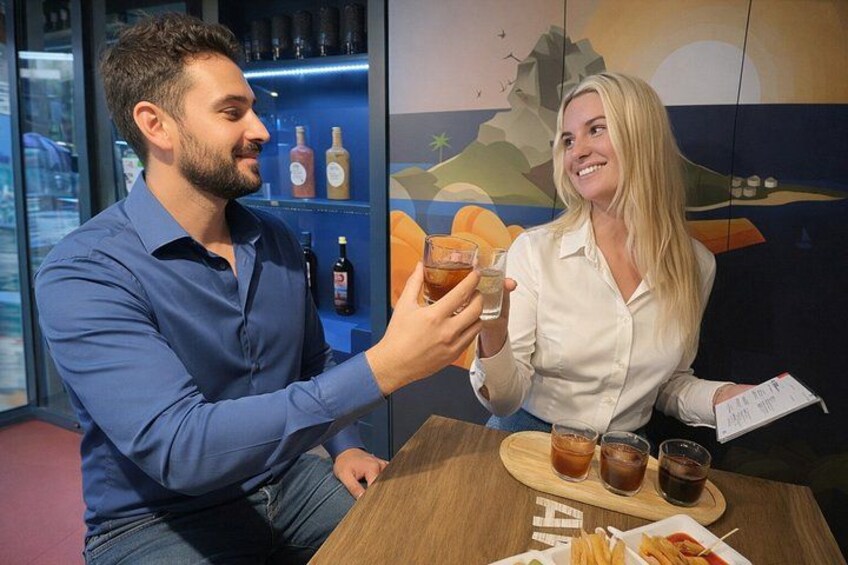 To personer skåler med drikkevarer ved et bord med en menu og en flaske sauce. 1