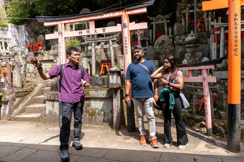 A group of people standing in front of a traditional Japanese shrine with stone steps and wooden torii gates. 4