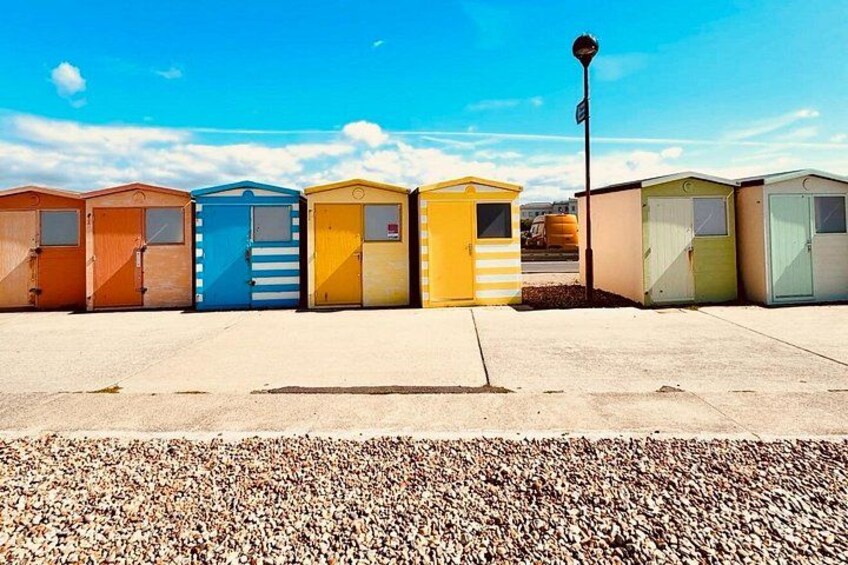 A row of colorful portable buildings, a clear sky, and a gravel ground. 3
