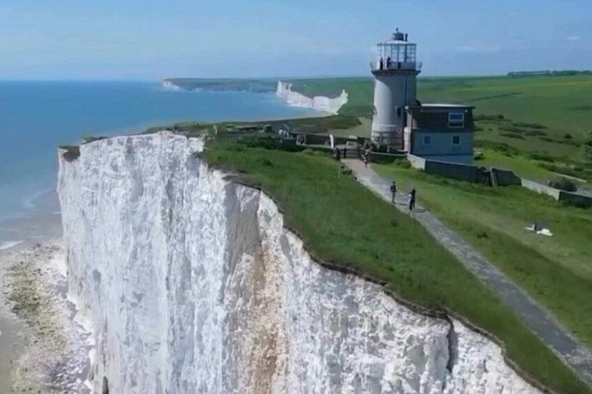 A coastal cliff, a lighthouse, and a grassy path. 2