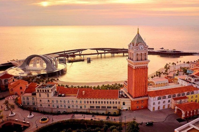 A coastal cityscape with a prominent clock tower, a modern bridge, and a historic building with a red roof. 2