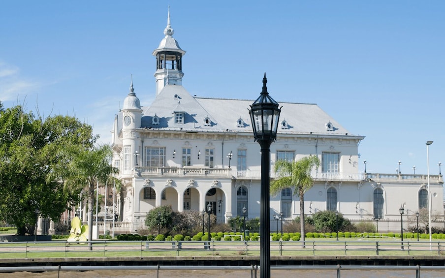 A large white building with a tower, arched windows, and a lamp post in the foreground. 3
