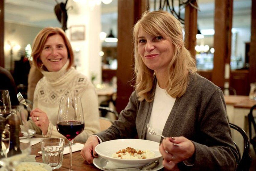 Two people dining at a restaurant with wine glasses and plates of food. 1