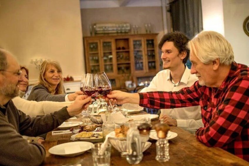 A group of people toasting with wine glasses at a dinner table. 1