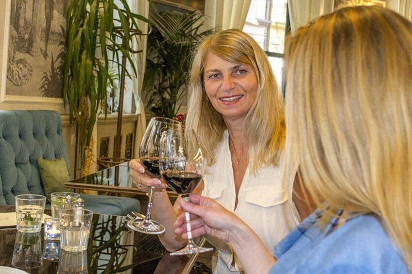 Deux personnes trinquent avec des verres à vin dans une pièce où se trouvent un canapé vert et une table en verre. 5