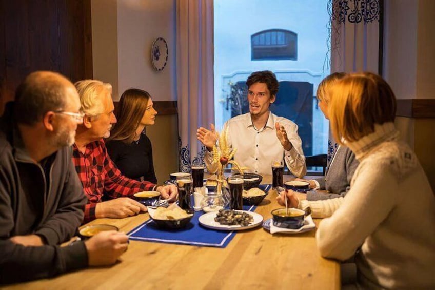 En grupp människor sitter runt ett träbord med mat och dryck. 2