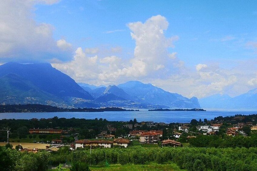 Eine Küstenstadt mit Bergen im Hintergrund, einem Gewässer und viel Grün im Vordergrund. 1