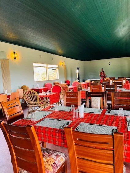 A restaurant with wooden tables and chairs, red and black checkered tablecloths, and a person standing in the background. 3