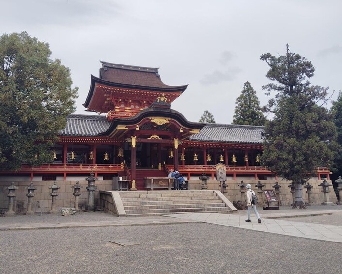 A traditional Japanese temple with a red and gold roof, stone lanterns, and a stone staircase leading to the entrance. 4