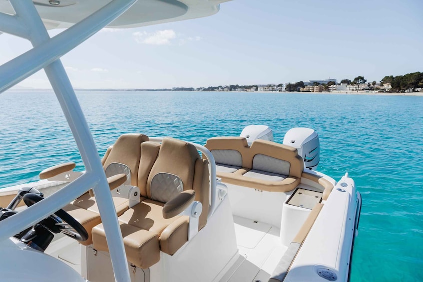 A boat with beige and white seating, a steering wheel, and a motor. 4