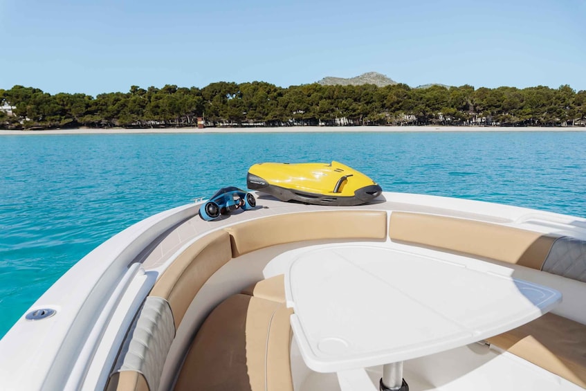 A boat with a yellow inflatable dinghy on the bow, beige cushions, and a white table. 2