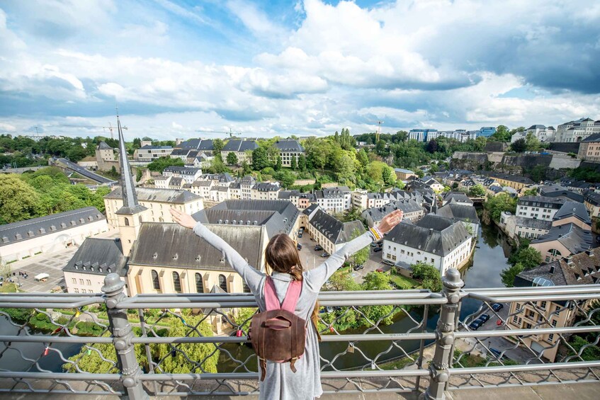 A person overlooking a town from a bridge with arms outstretched. 3