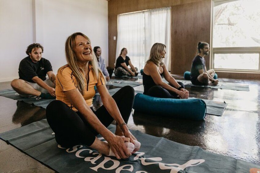Personas sentadas sobre esterillas de yoga en una habitación con ventanas amplias. 3