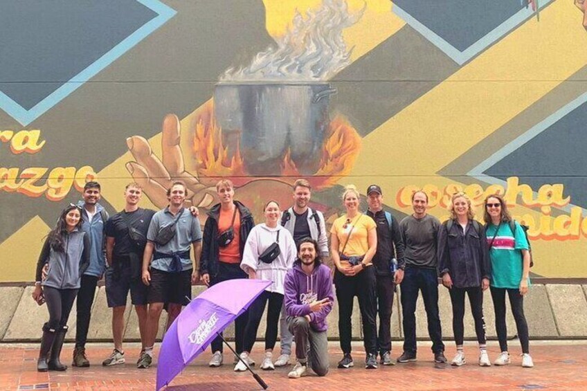 A group of people standing in front of a mural with a pot and flames. 2