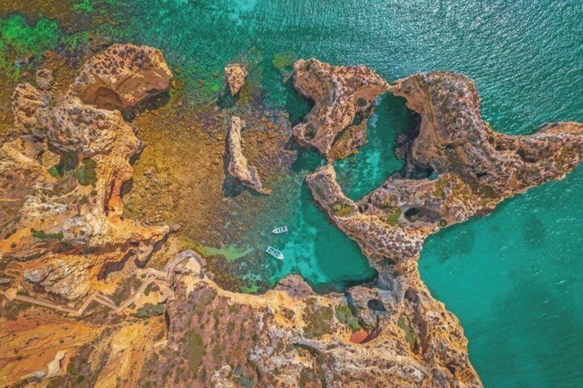 An aerial view of a rocky coastline with clear turquoise waters and scattered vegetation. 3