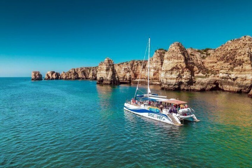 A boat named 'Discover' on calm waters near rocky cliffs. 1