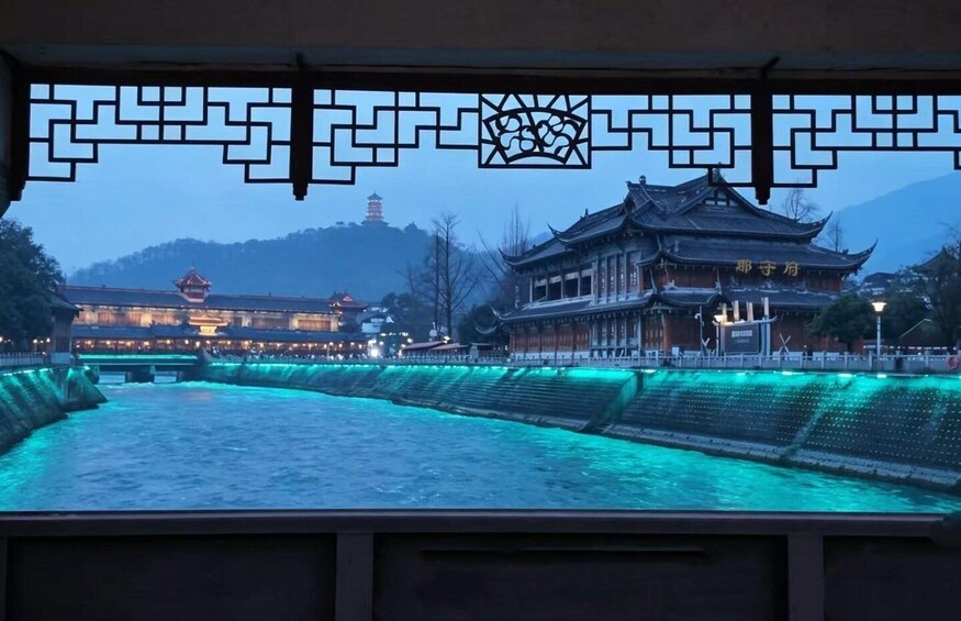A traditional Chinese building with a pagoda in the background, illuminated by blue lights. 2